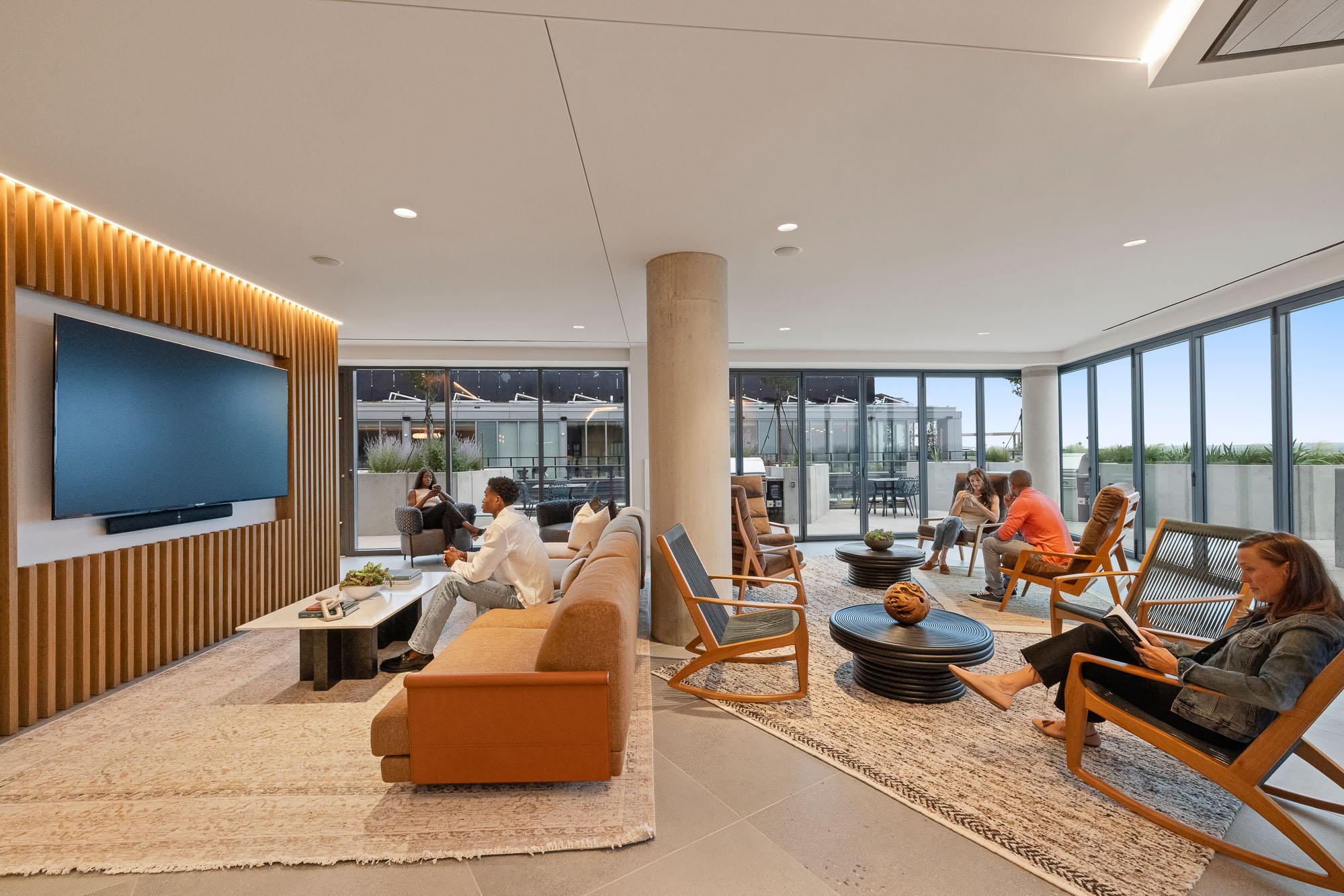 A group of people sitting in a room with a large screen.