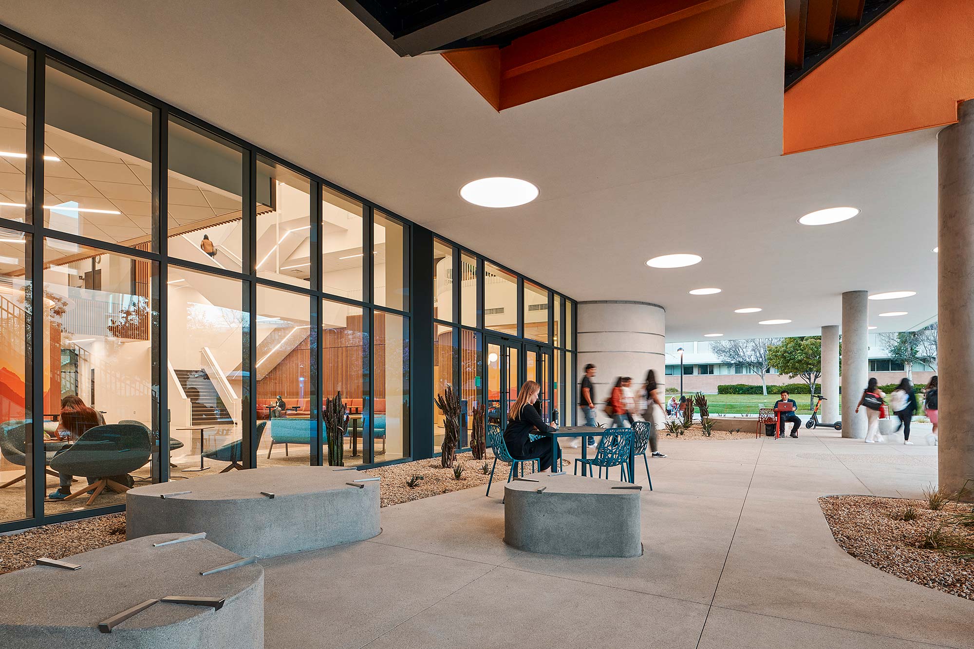 A building with glass walls and people walking around.