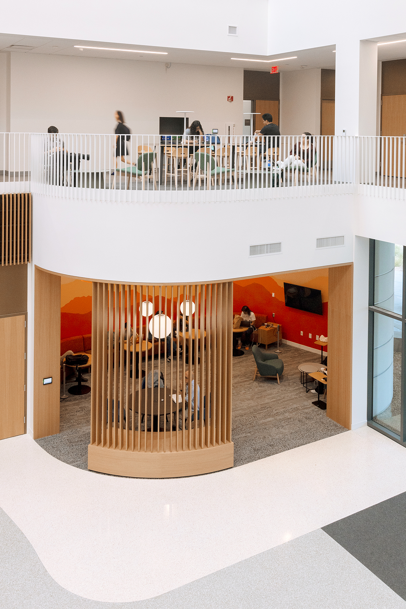 A room with a wood door and a wood railing with people in it.
