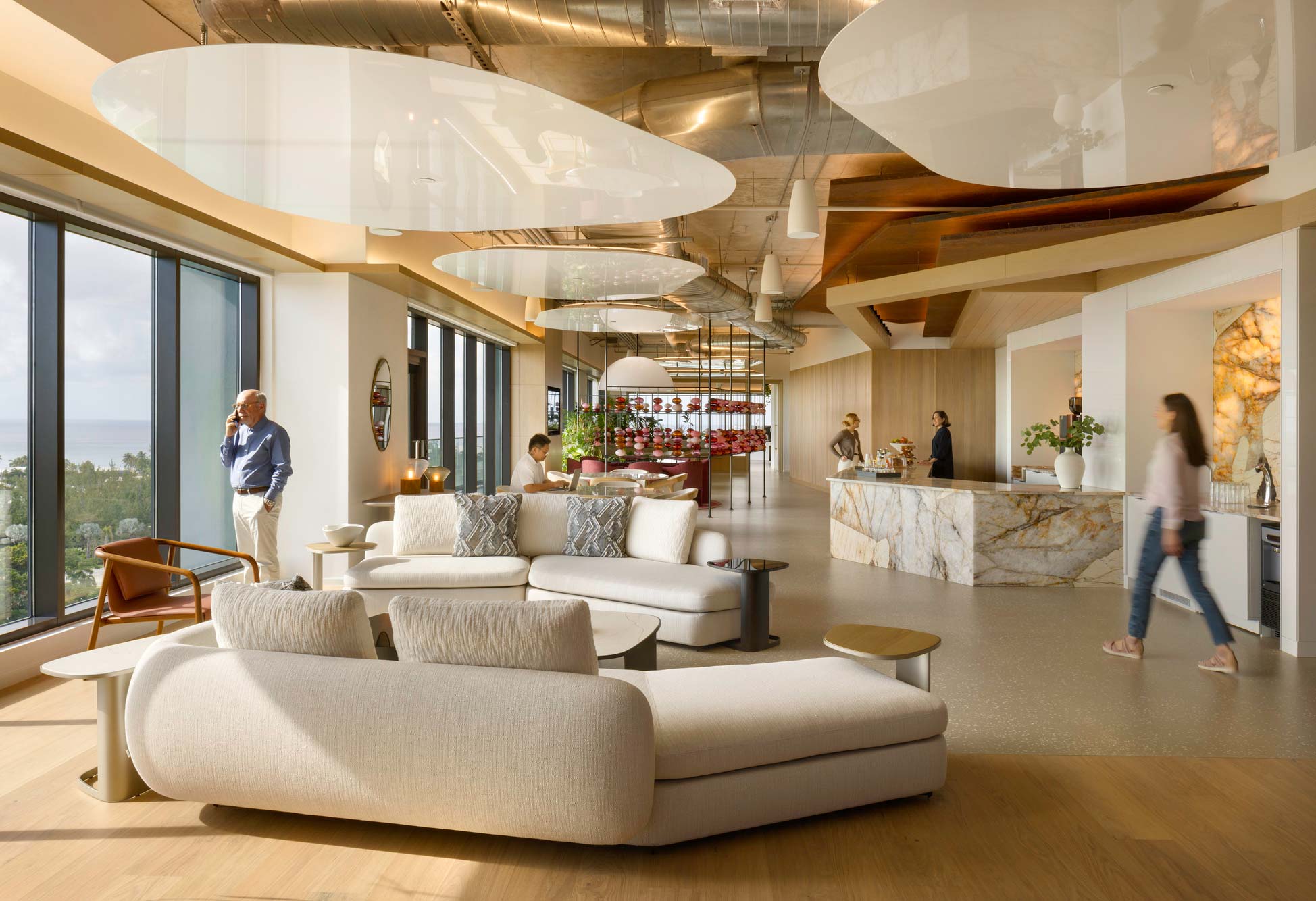 A large room with a large white couch and a couple people.