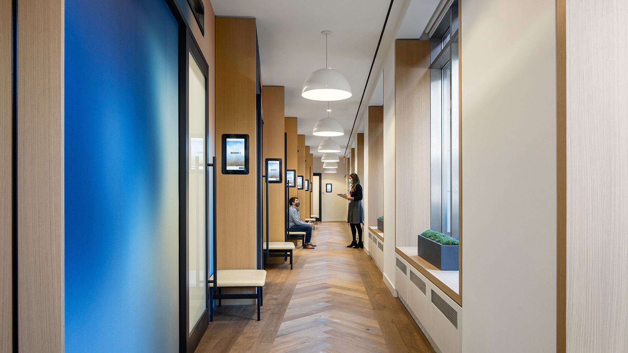 A woman taking a picture of a man sitting in a chair.