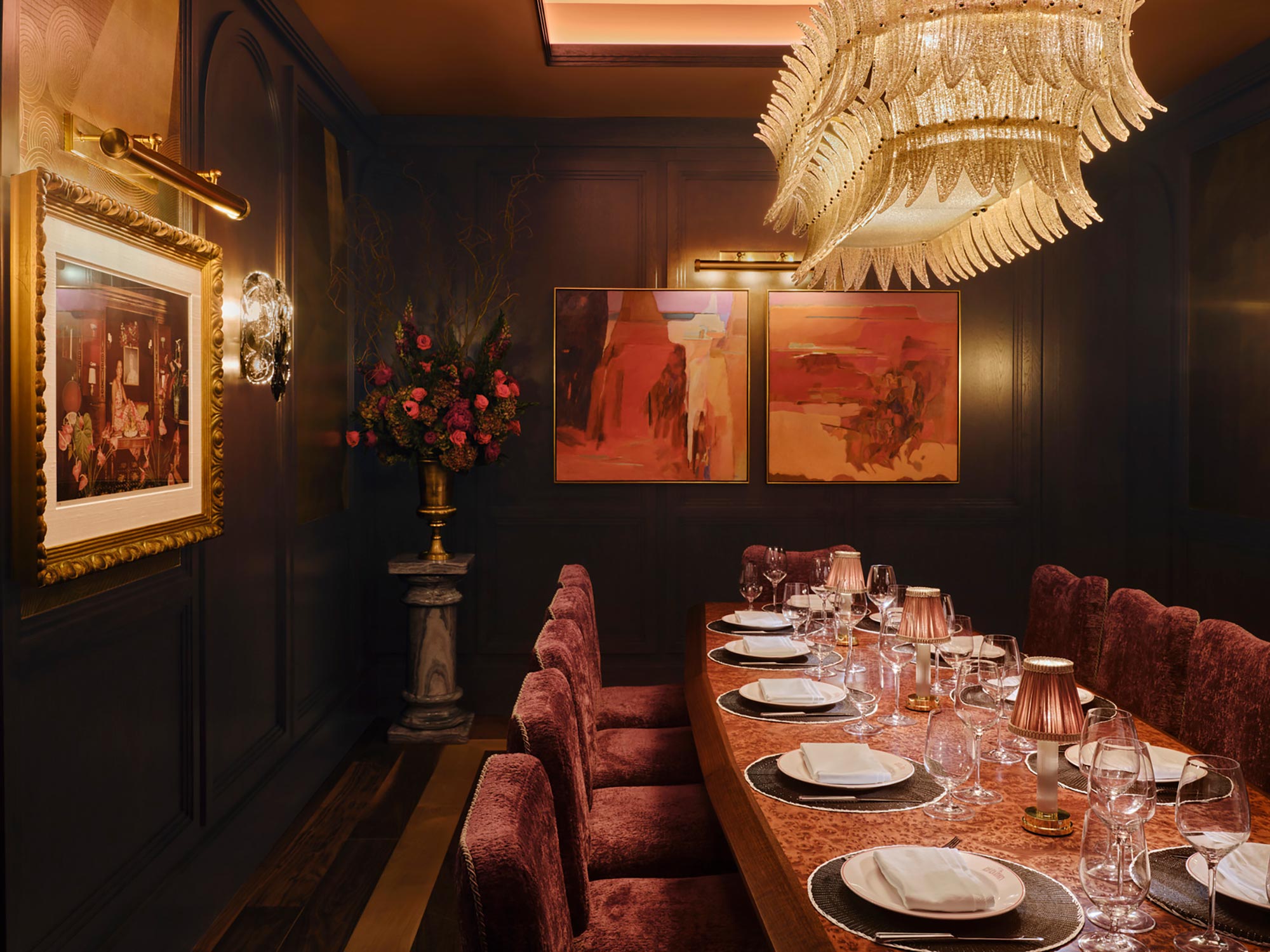 A dining room with a chandelier and a table with plates.