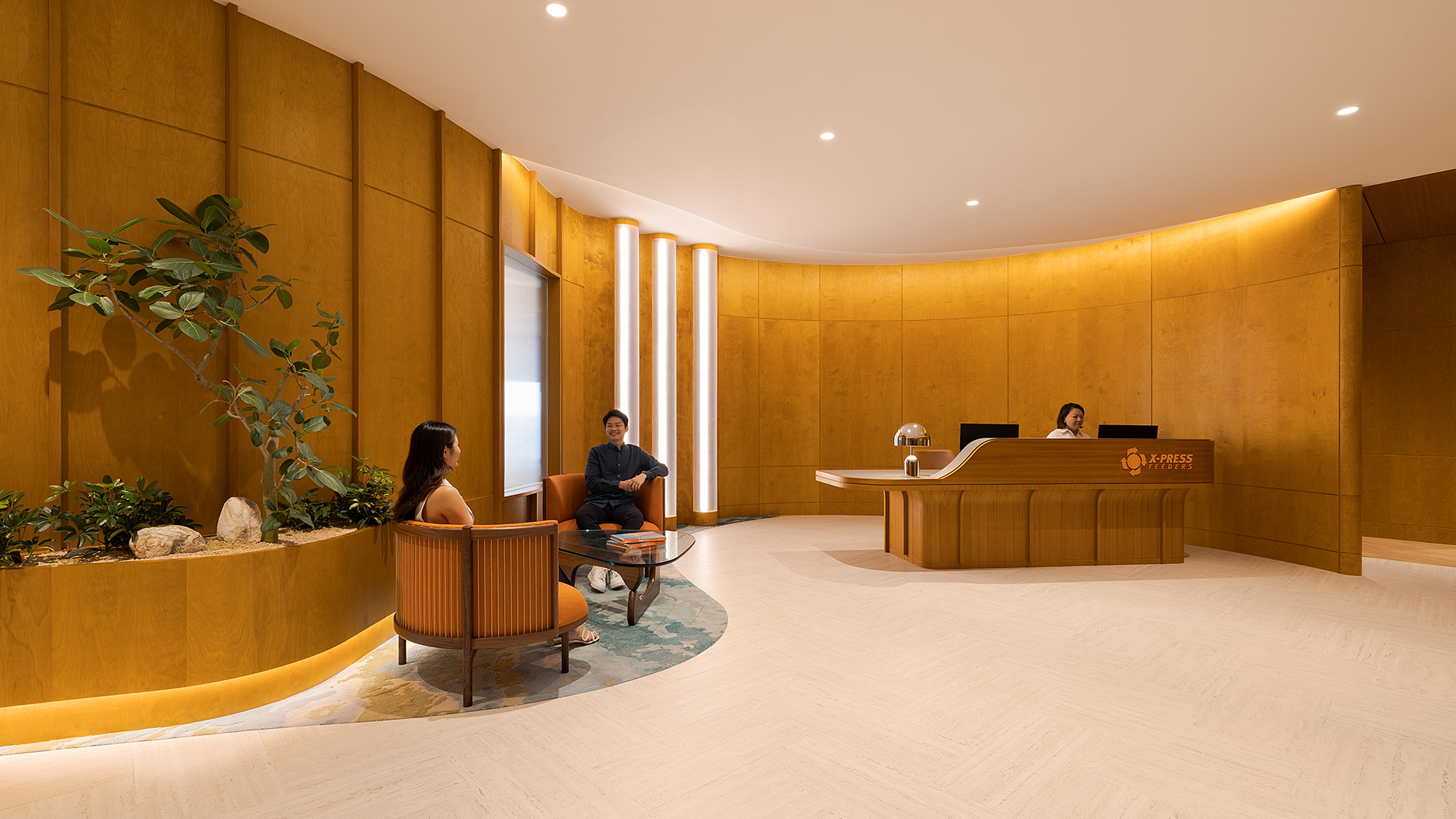 A man and woman sitting in a room with a desk and chairs.