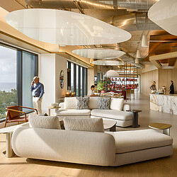 A room with a couch and a table with chairs and a couple people.