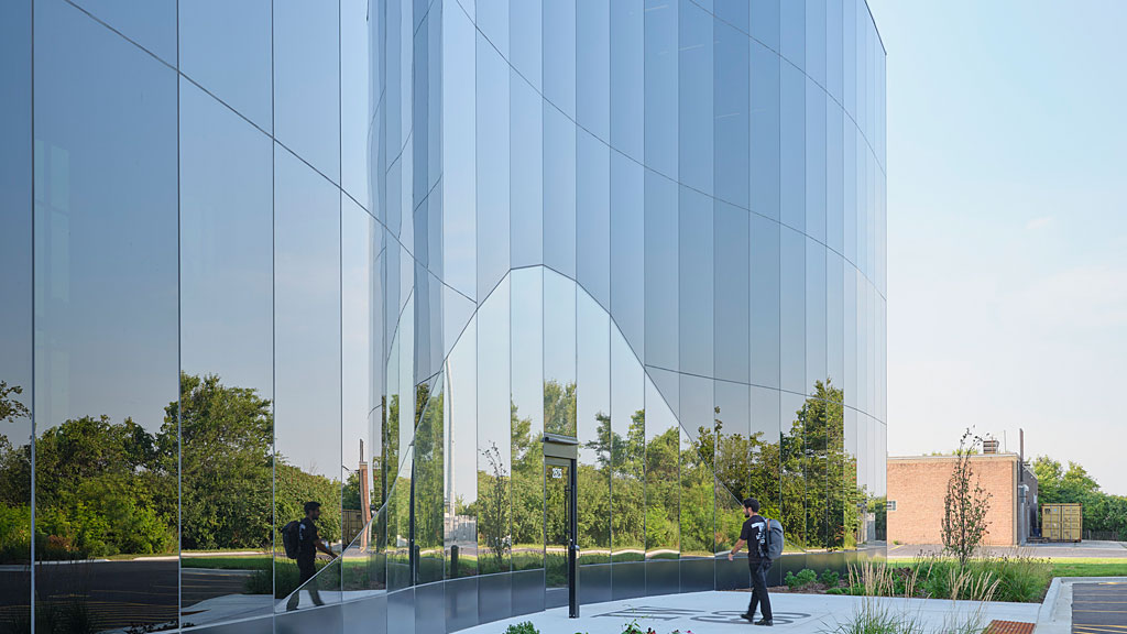 A large glass building with a few people walking around.