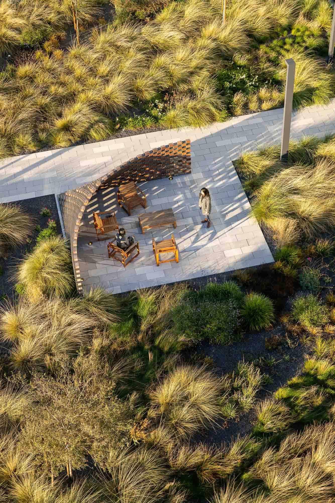 A person walking on a path with a building and trees on the side.