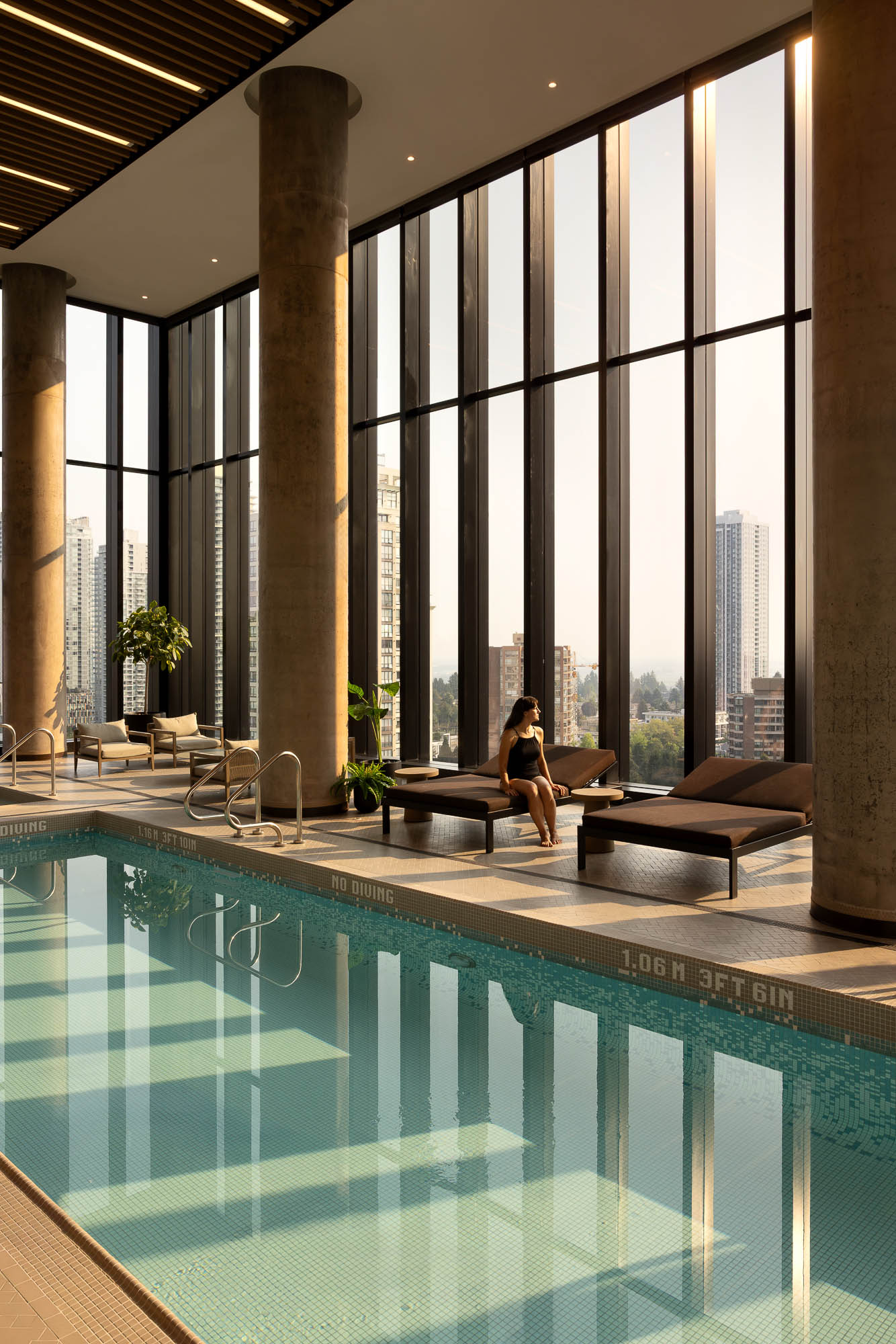 A person sitting on a bench by a pool.