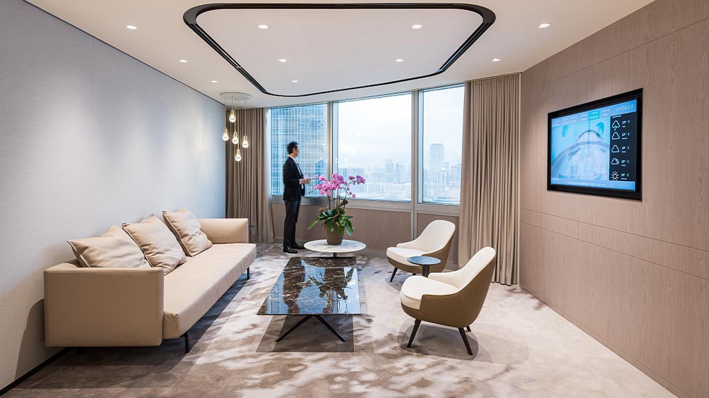 A person standing in a room with a large tv and chairs.
