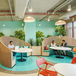 A couple of people sitting at a table in a room with plants.