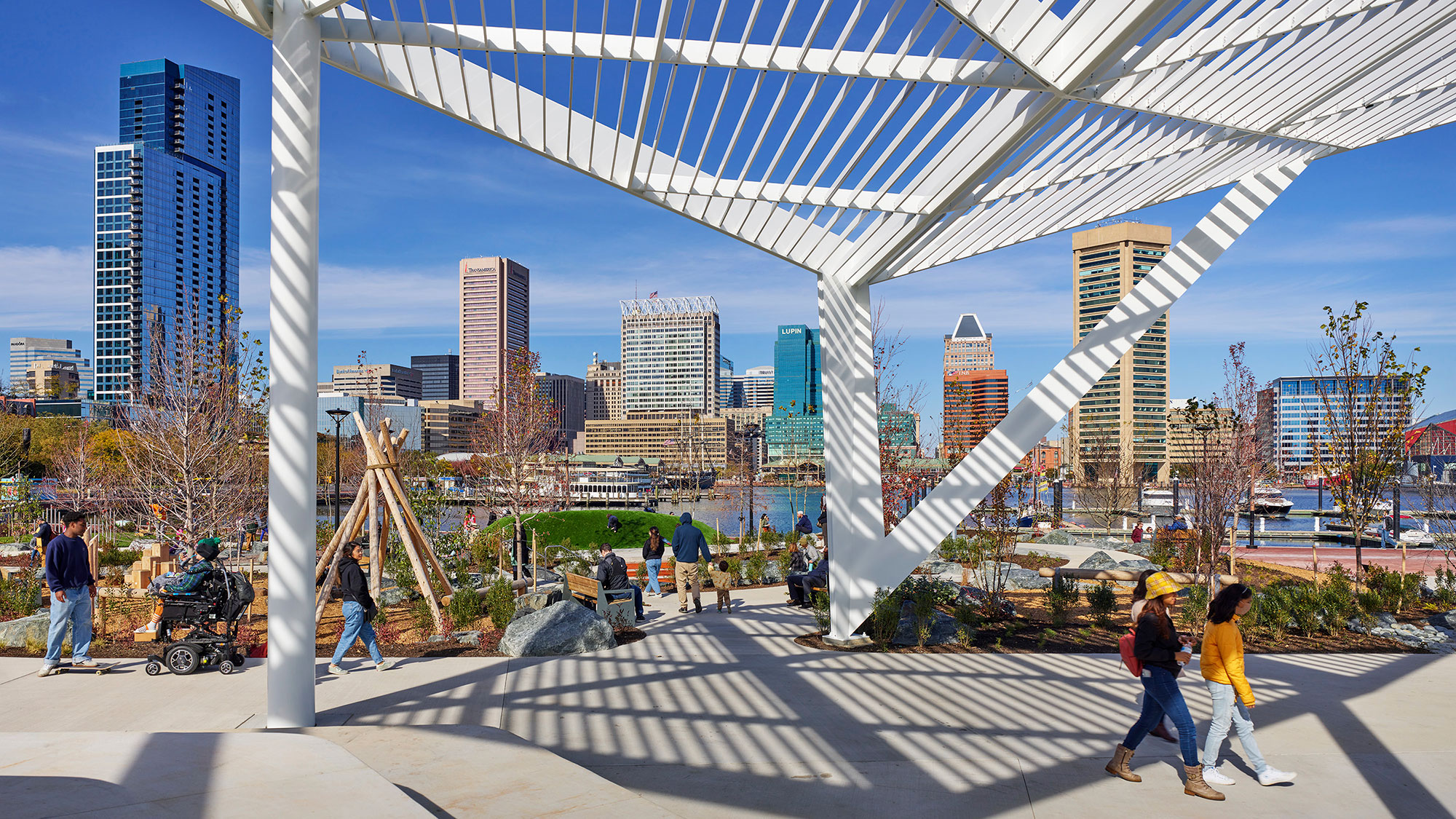 A group of people walking around a large structure with a city in the background.