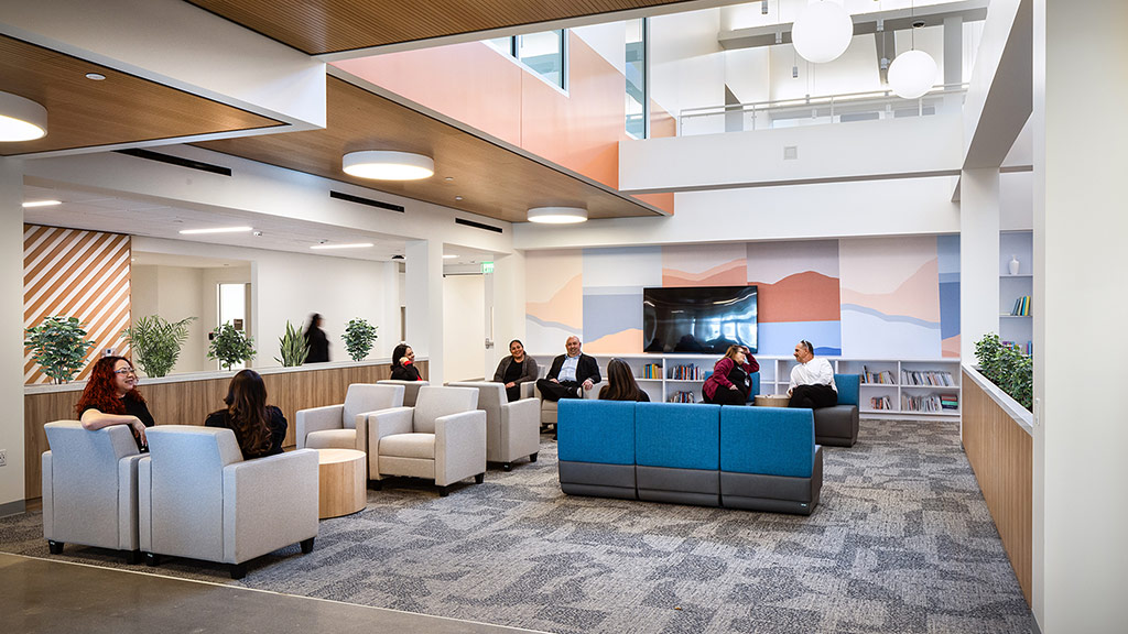 A group of people sitting in a room with a large screen.
