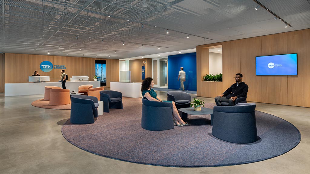 A group of people sitting in chairs in a room with a large screen.
