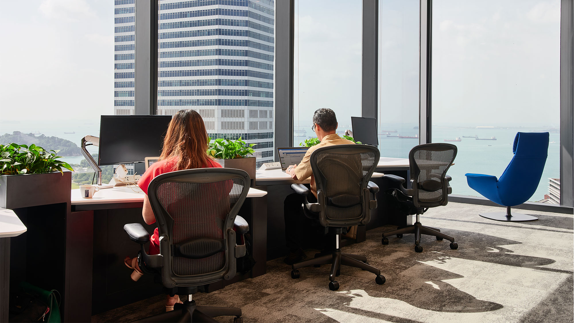 A man and a woman sitting at a table with computers.