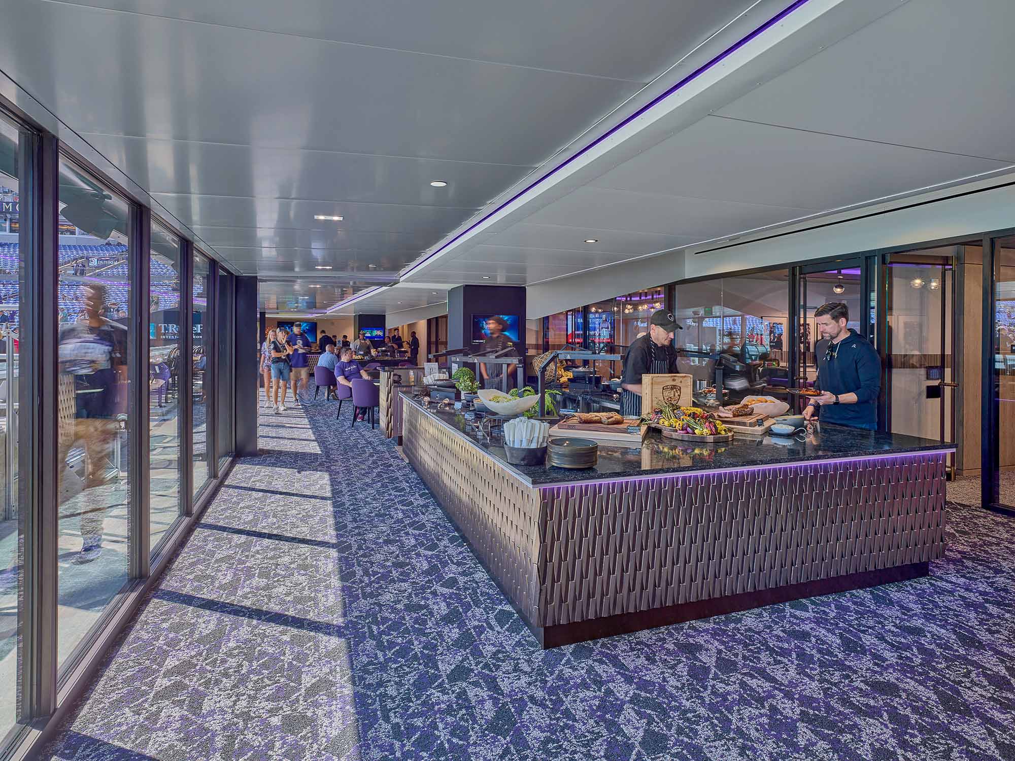 A group of people in a large room with food on the table.