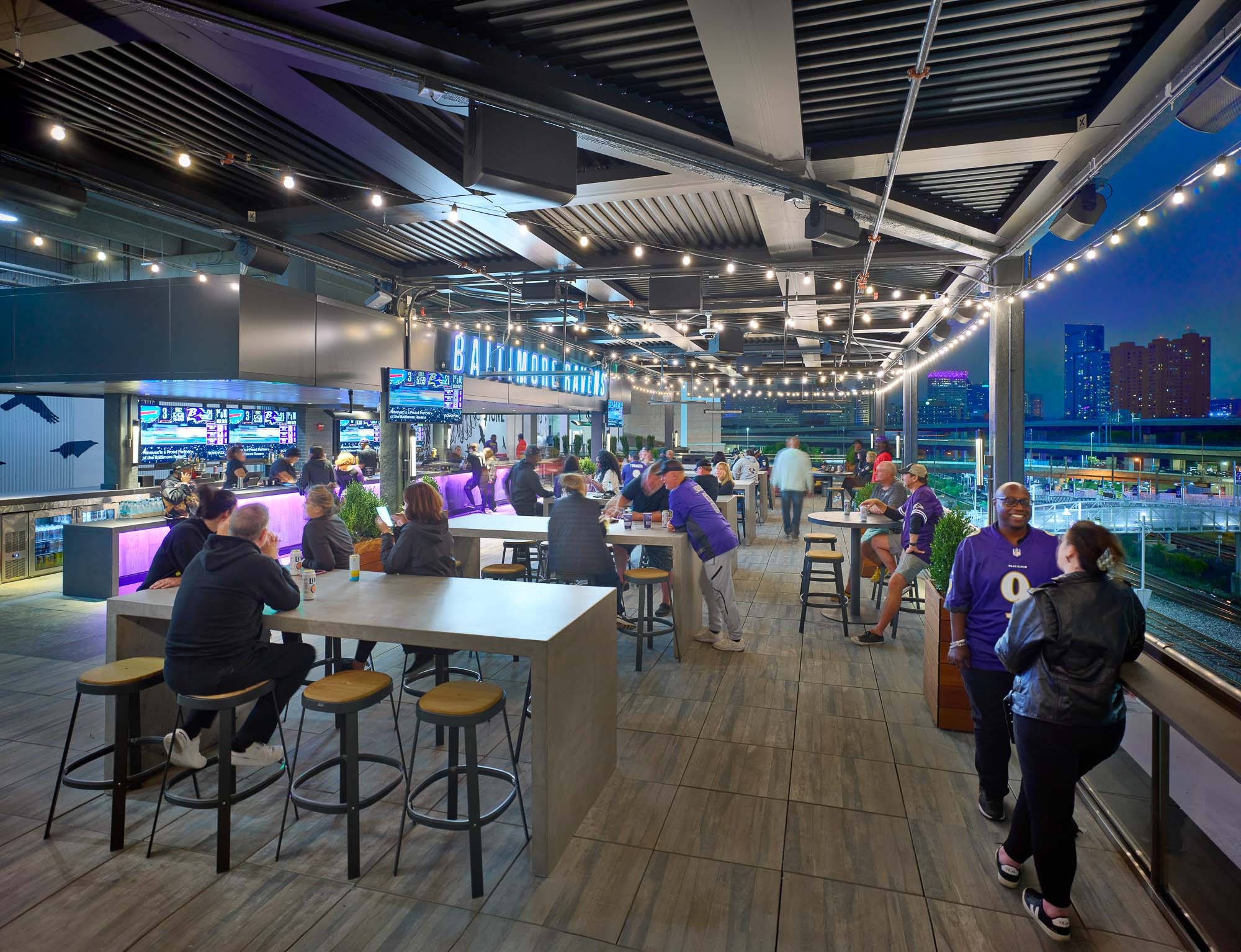 A group of people in a large room with tables and chairs.