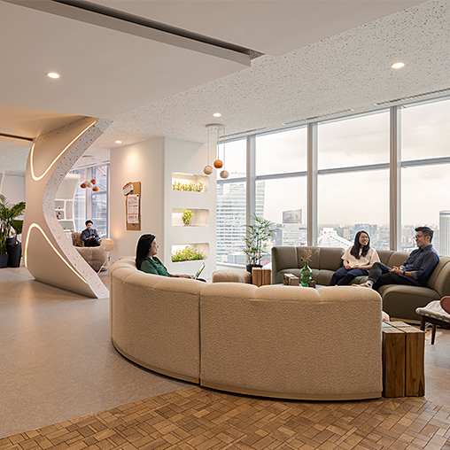 A group of people sitting on a couch in a room with windows.