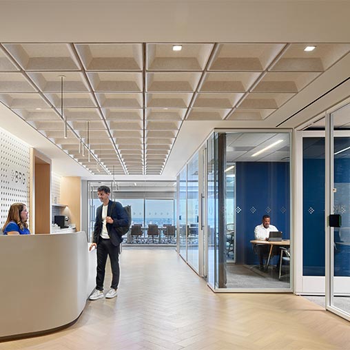 A person standing in a room with glass doors and people sitting at tables.