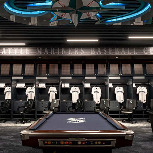 Seattle Mariners clubhouse lockers with white baseball jerseys and chairs with Mariners logo