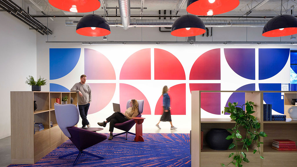 A group of people in a room with a red and white wall.