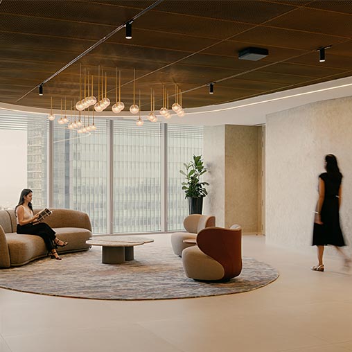 A woman standing in a room with a man sitting on a couch.