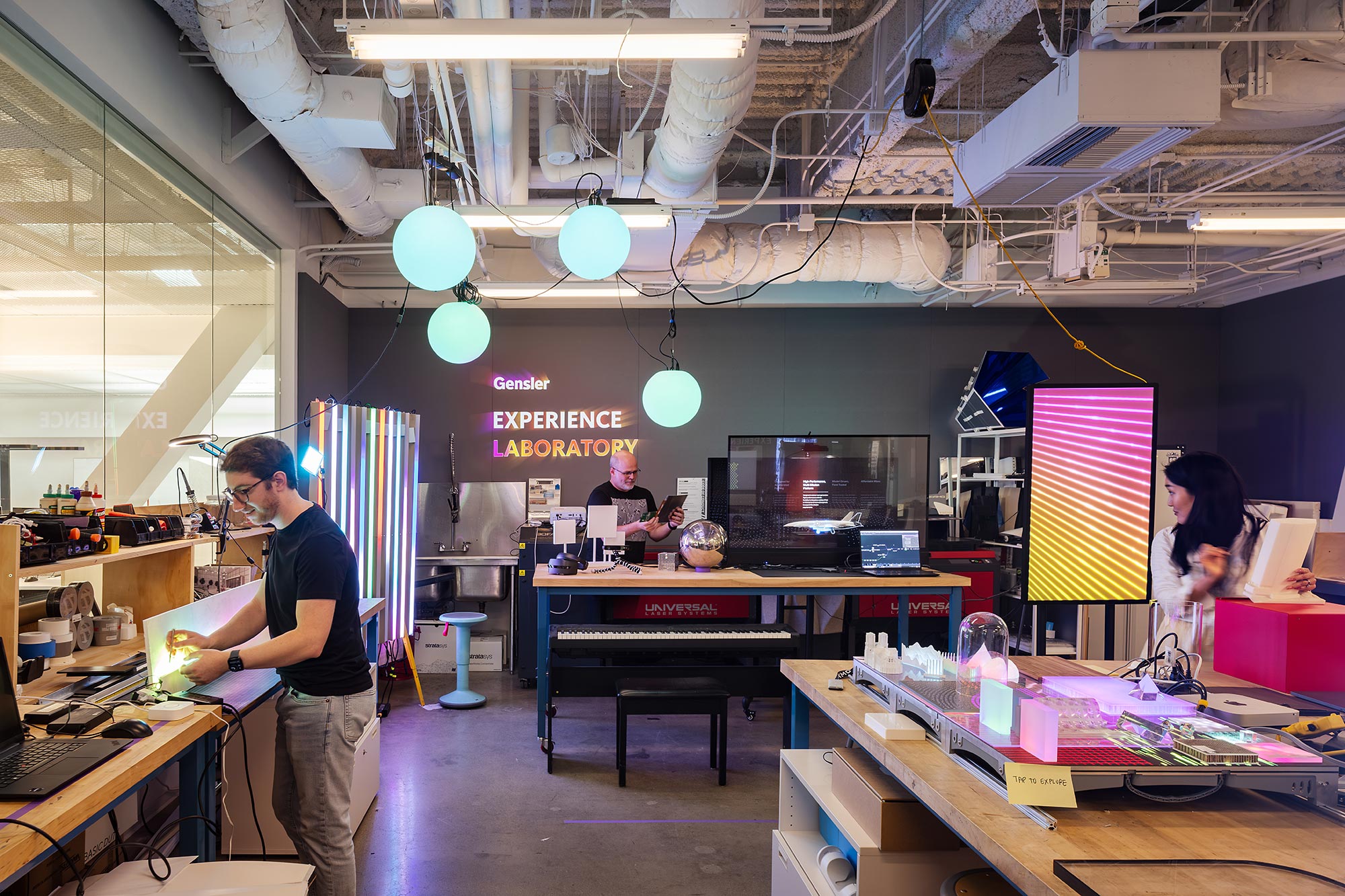 A person playing a piano in a room with other people.