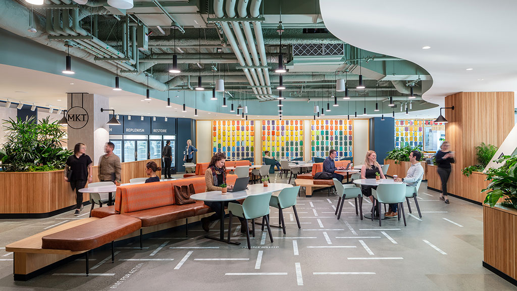 A group of people sitting at tables in a large room with a large glass ceiling.