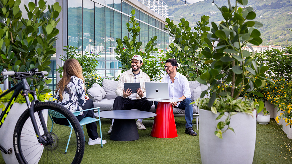 A group of people sitting on a bench with a laptop.