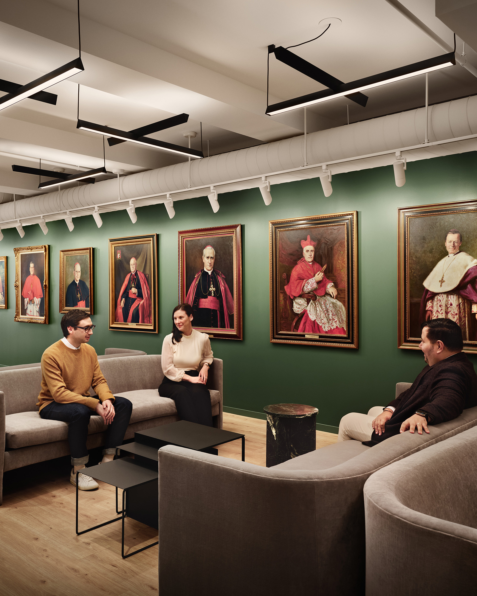 A group of people sitting on couches in a room with art on the walls.