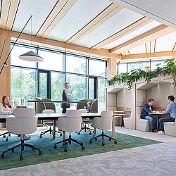 A group of people sitting around a table in a room with windows.