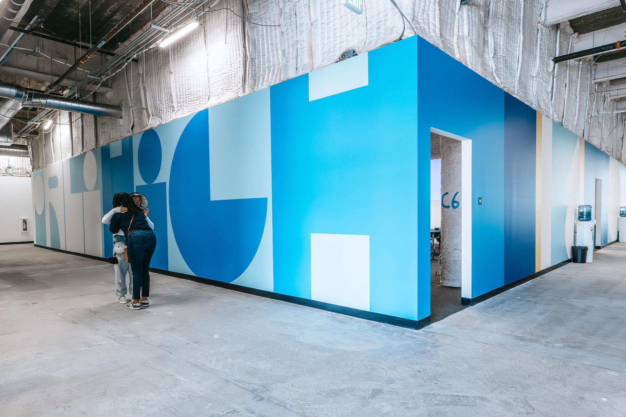 A couple of people standing in a large room with blue walls.