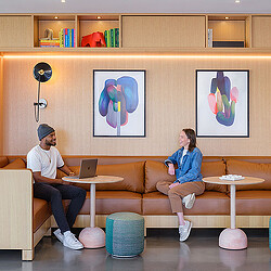 A man and a woman sitting on a couch with laptops.