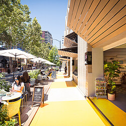 A couple of people sitting at a table outside a building.