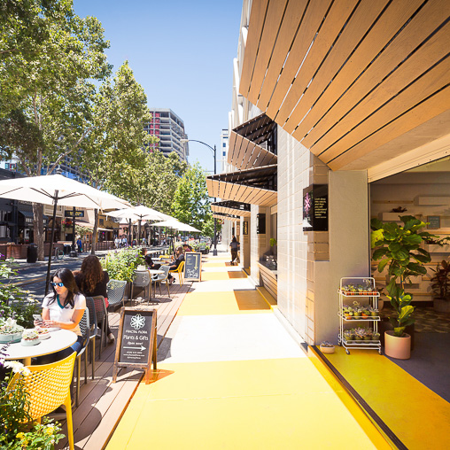 A couple of people sitting at a table outside a building.