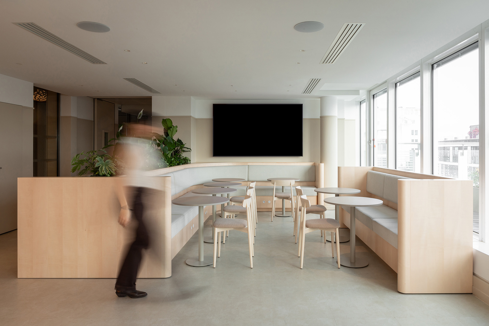 A person standing in a room with a tv and chairs.
