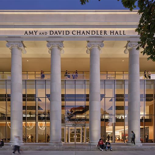 A building with pillars and people walking around.