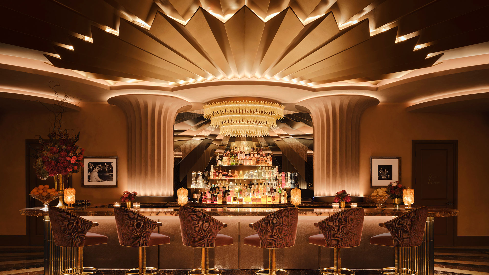 A fancy dining room with chandelier and chairs.