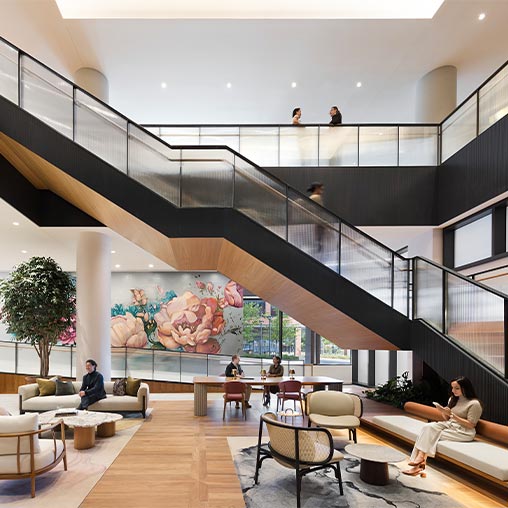 A group of people sitting on a couch in a room with a staircase.
