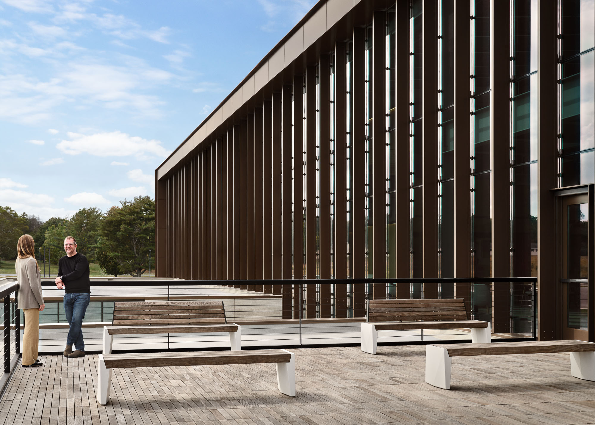 A couple of people standing next to a building with benches.