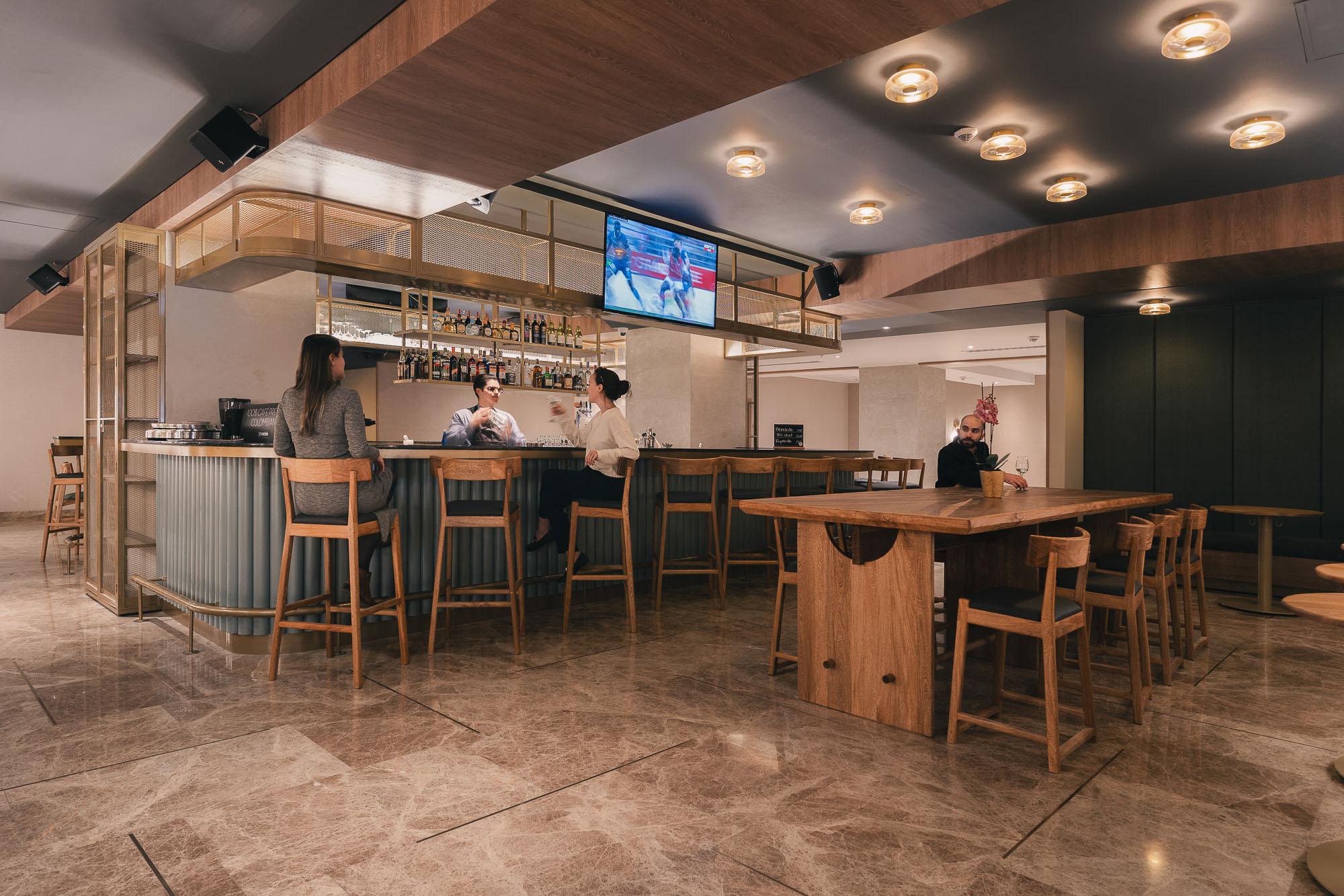 A group of people sitting at a table in a room with a large screen.