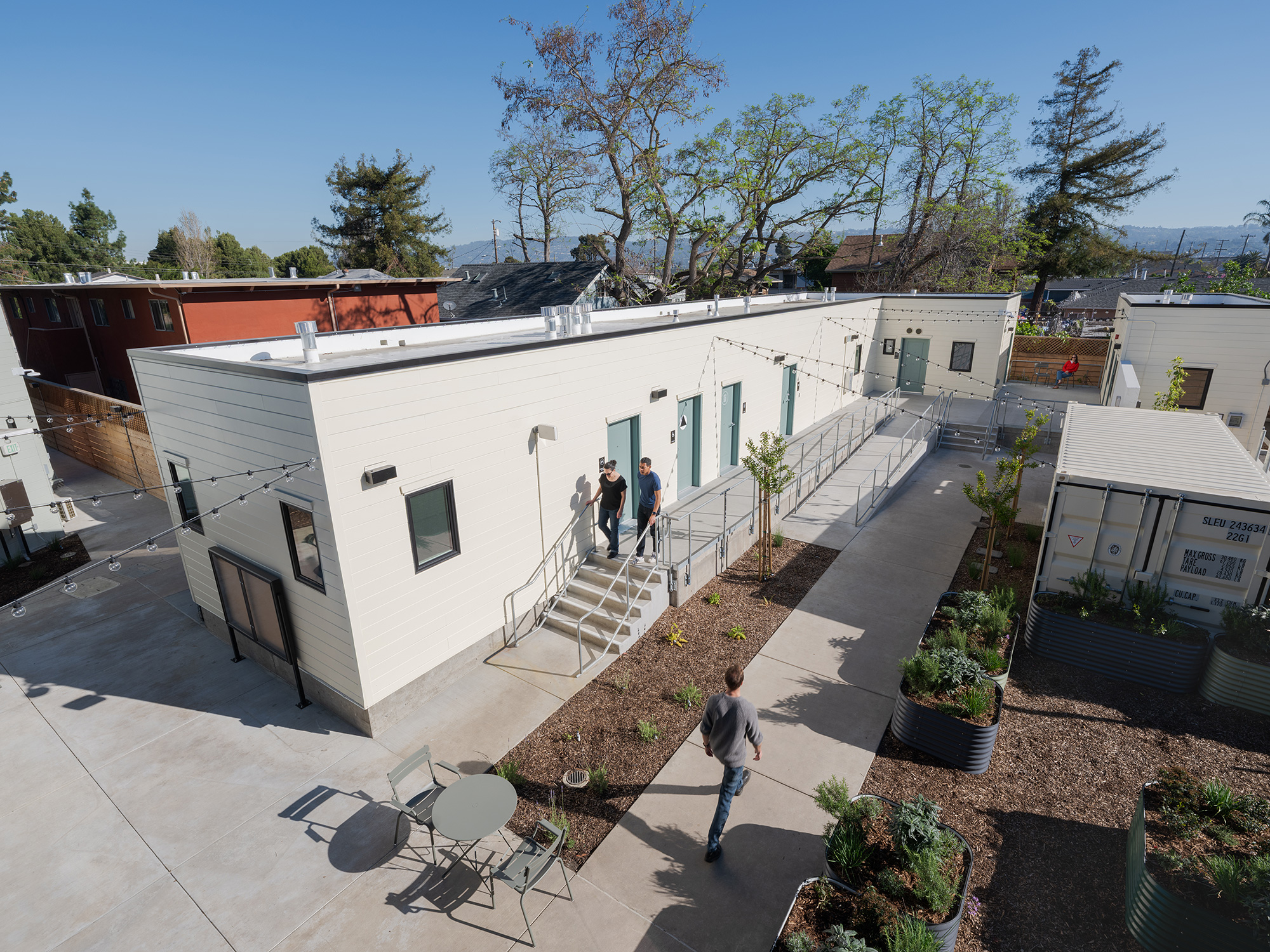 A group of people walking around a white building.