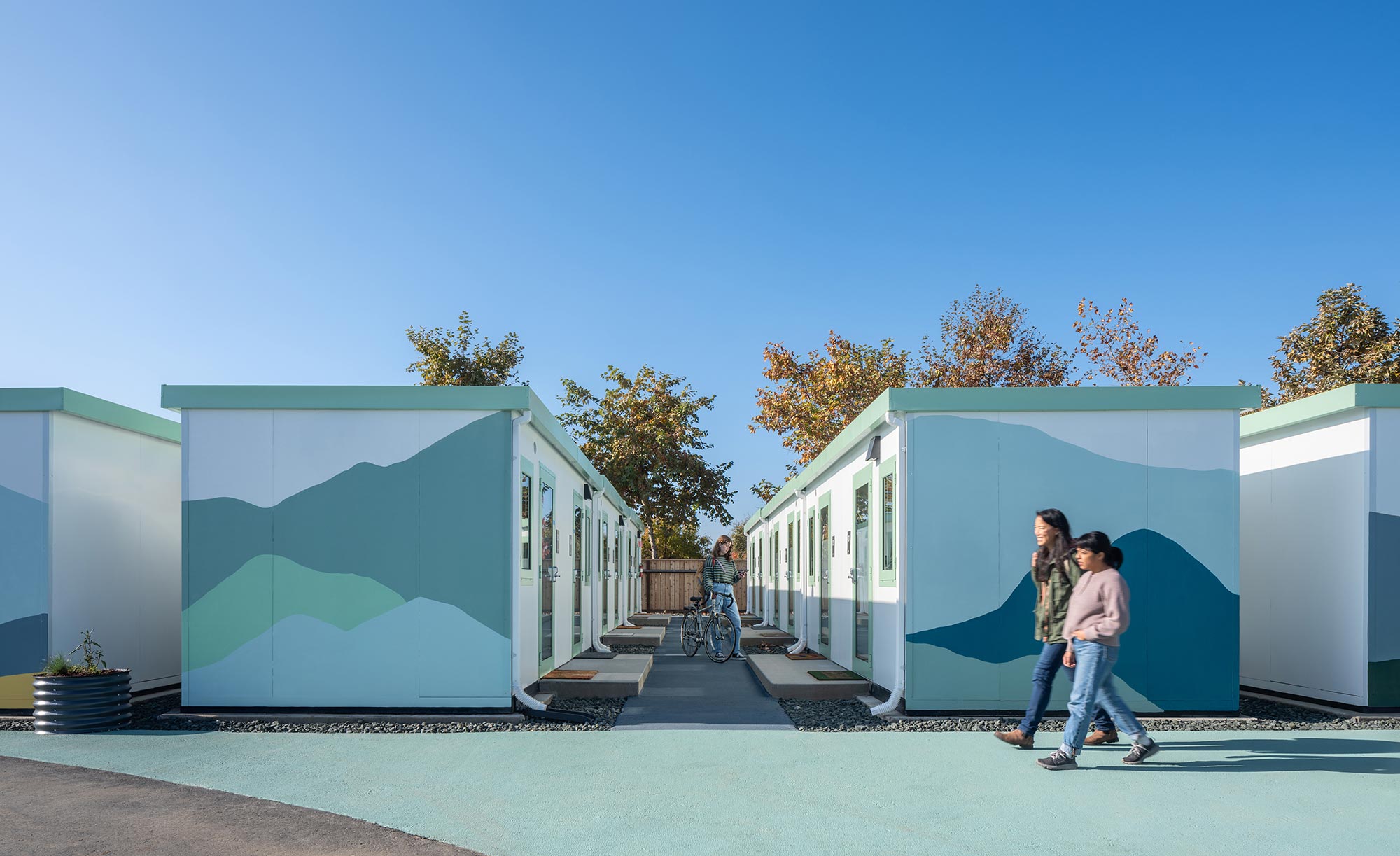A couple of people walking by a building with a blue roof.