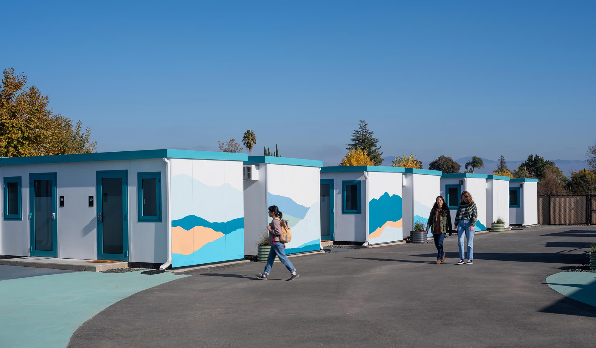 A group of people walking by a row of blue buildings.