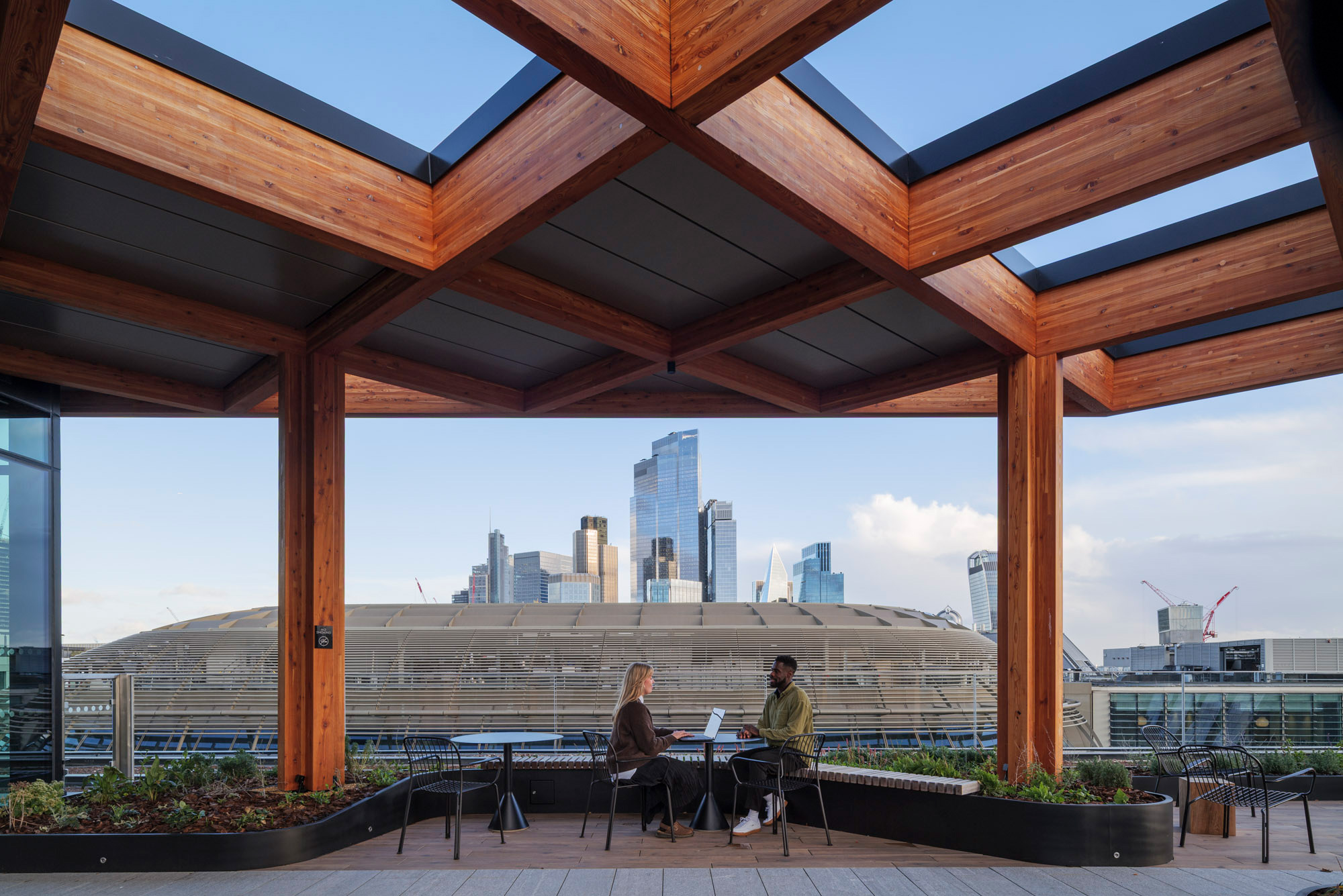 A couple sitting at a table in front of a window overlooking a city.