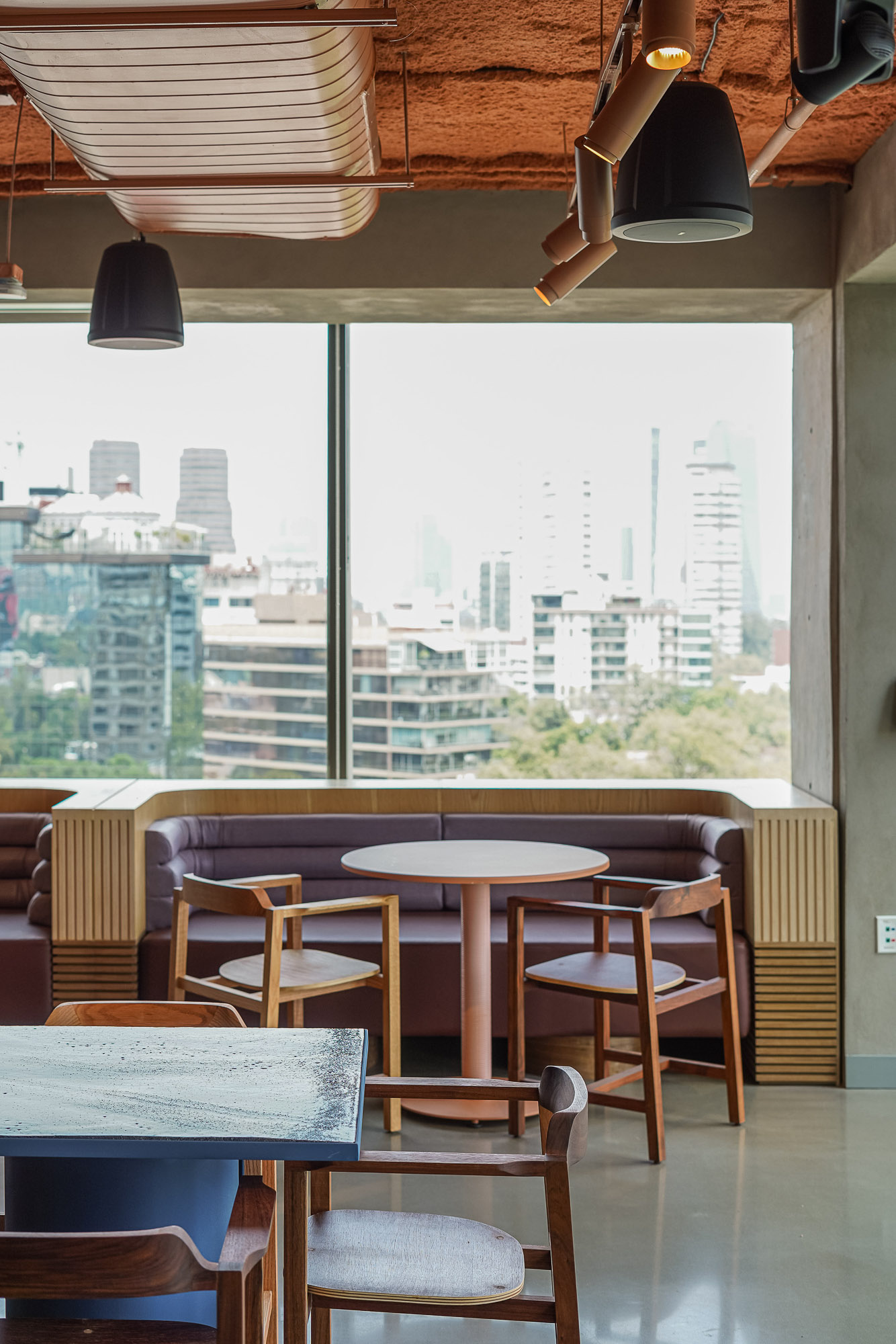 A room with tables and chairs and a window with a view of a city.