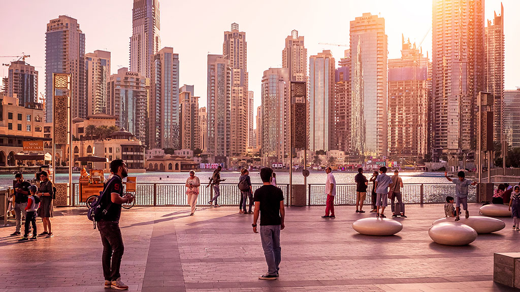 A group of people standing in a plaza with a city skyline in the background.