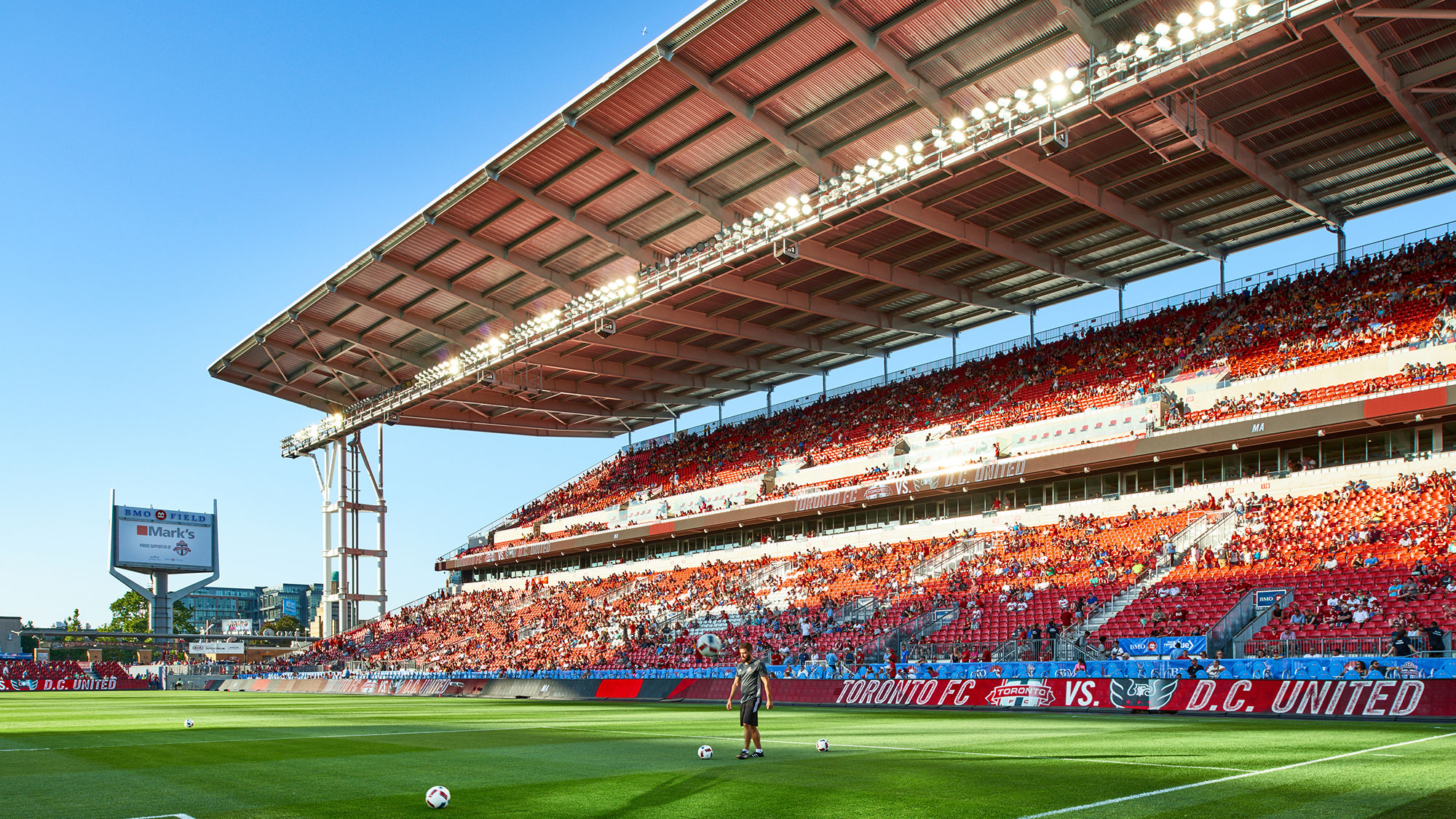 A person on a field with a stadium in the background.