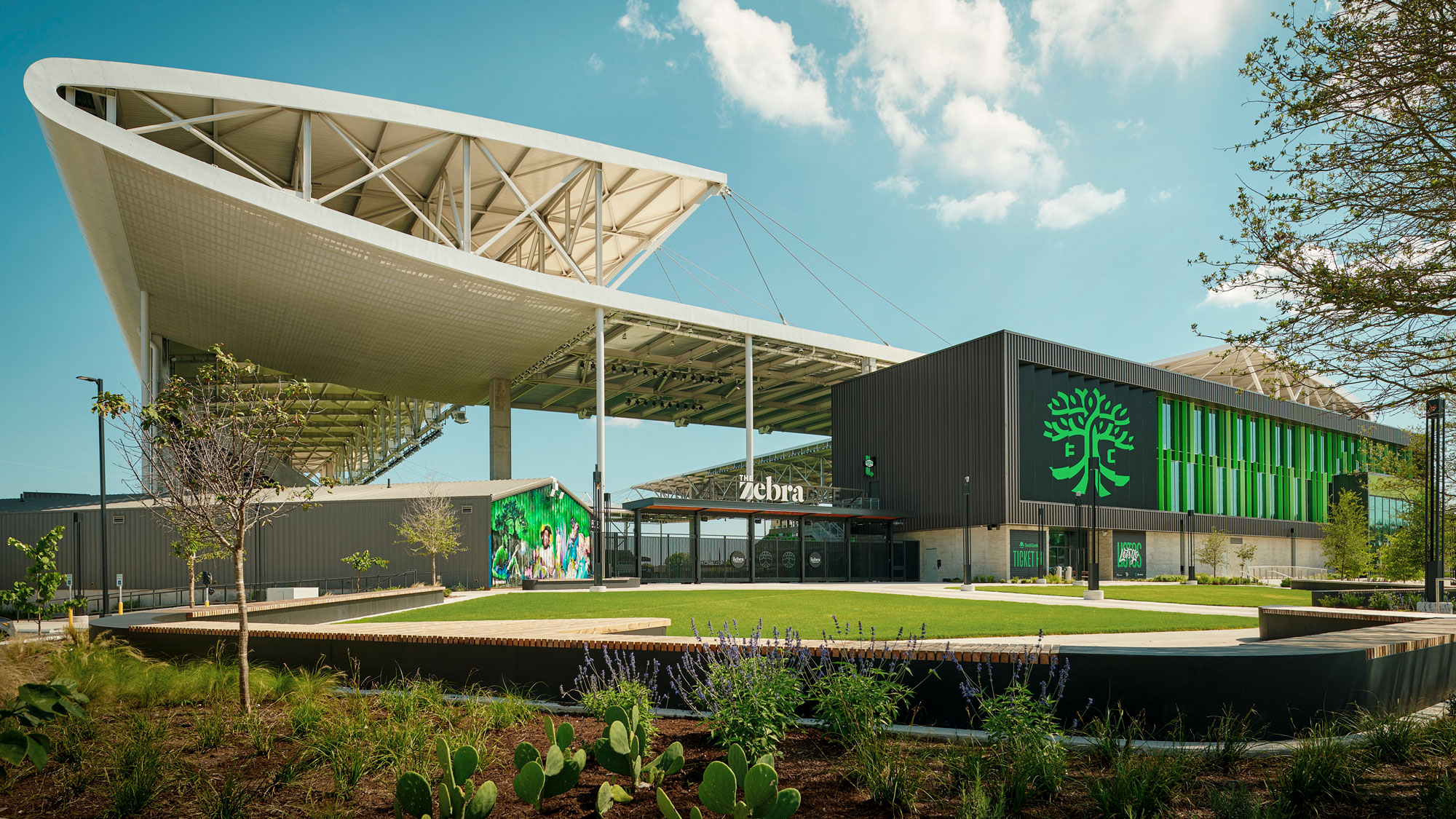 Exterior image of a soccer stadium with a swooping metallic roof.