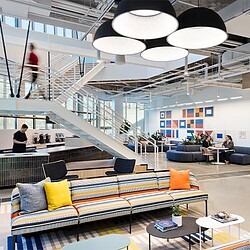 A room with a staircase and a couch and a table with people sitting at it.