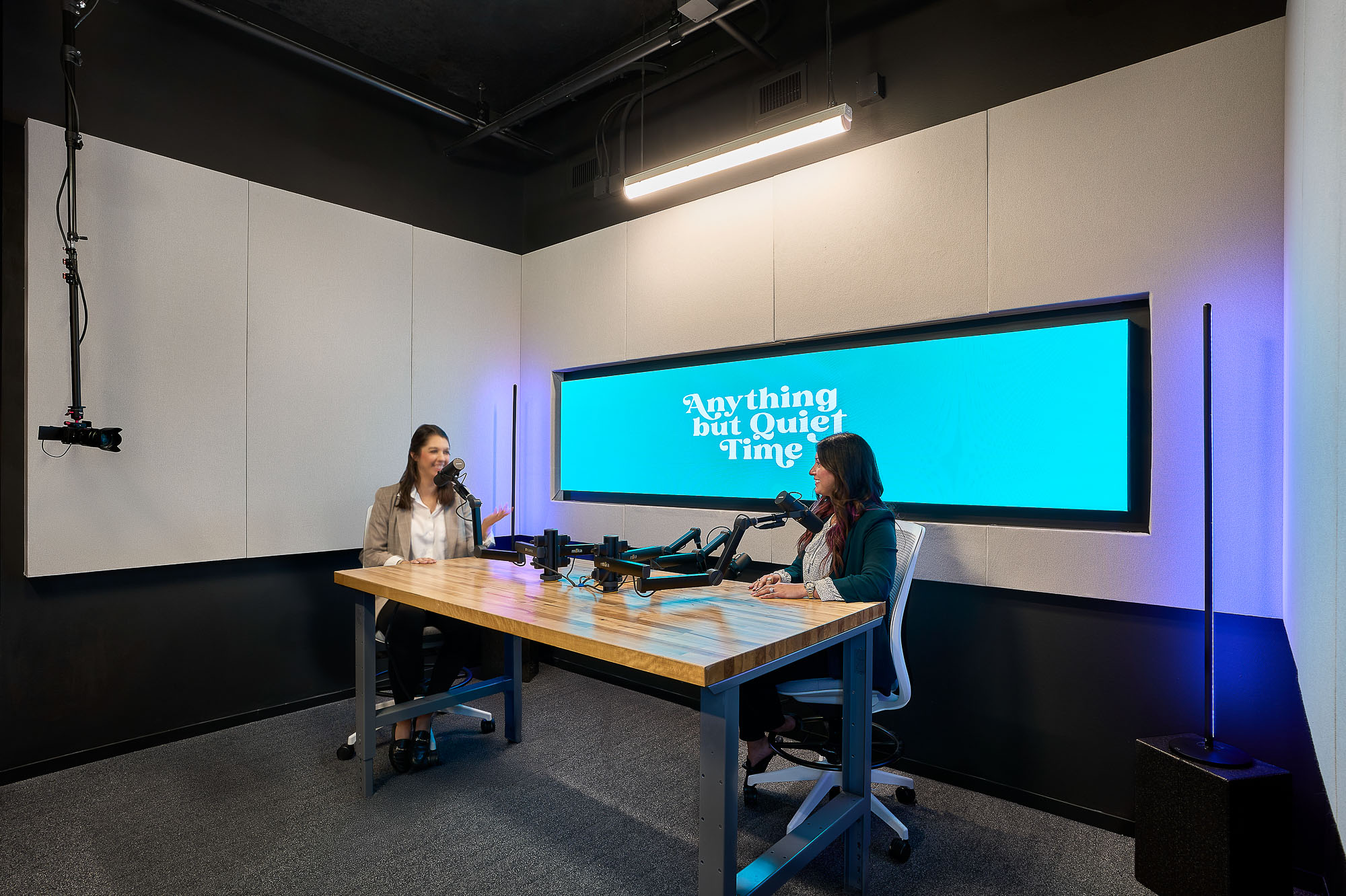 A person sitting at a table with a projector screen behind the.