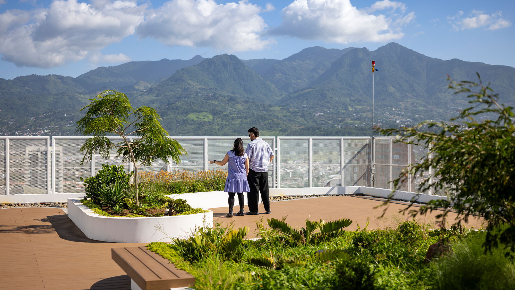 A man and woman standing on a balcony overlooking a body of water.